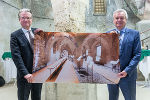 LH Christopher Drexler und LH-Stv. Anton Lang in der gotischen Einsäulenhalle der Grazer Burg mit der Visualiserung, wie der Raum am Ende der Revitalisierung aussehen könnte.